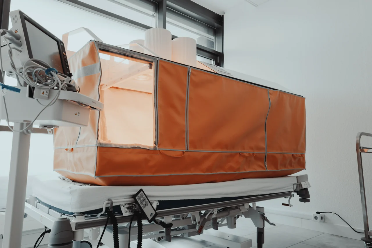 Orangefarbenes Hyperthermie-Gerät aufgebaut auf einem Behandlungsbett