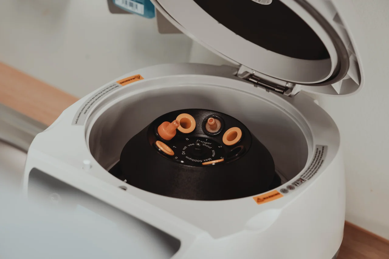 Geöffnete Laborzentrifuge mit Röhrchen und orangefarbenen Verschlüssen