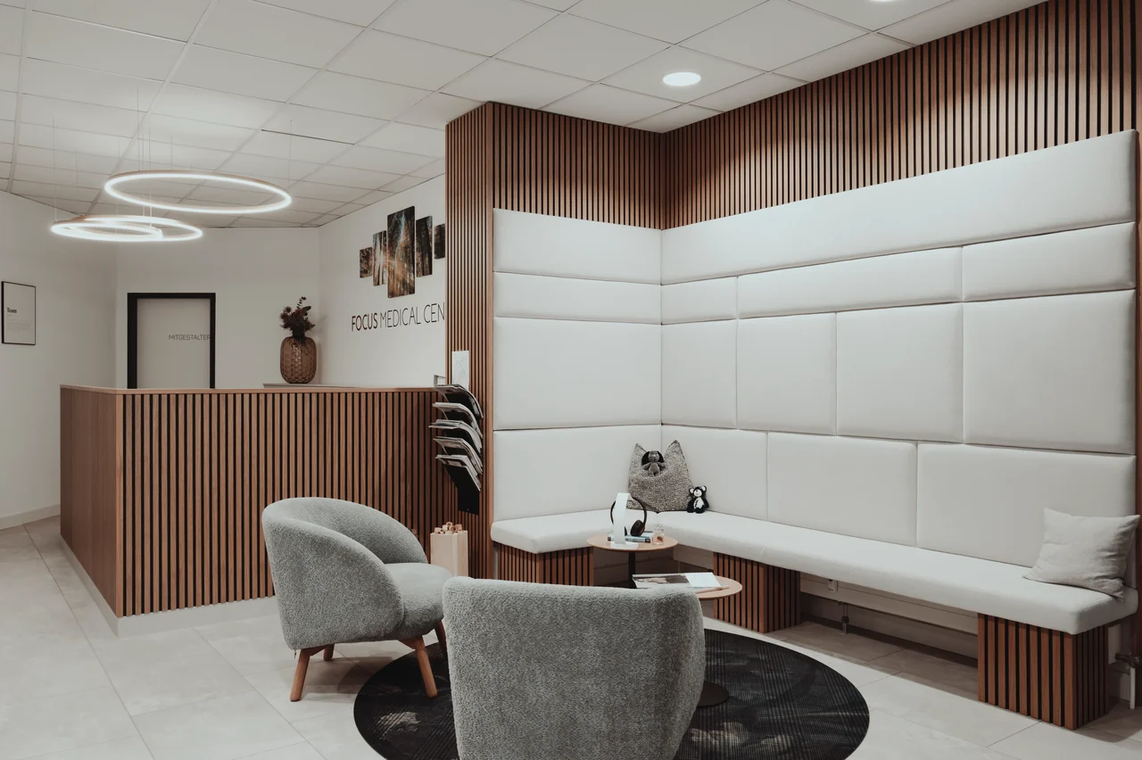 Empfangsbereich mit Holztresen und Loungesesseln in der Praxisklinik.