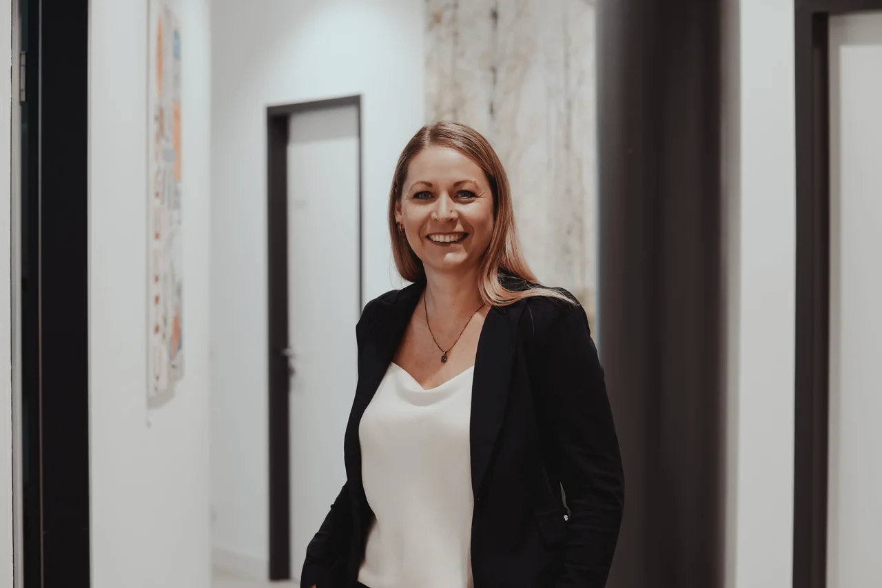 Melanie Hils lächelt breit im Flur der Praxisklinik, Nahaufnahme.